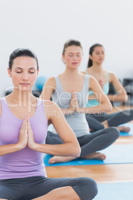 Women in Namaste position with eyes closed at fitness studio