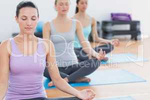 Women in lotus posture with eyes closed at fitness studio