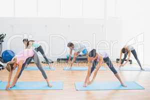Sporty class doing pilate exercises in fitness studio
