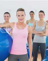 Instructor holding exercise ball with fitness class in backgroun