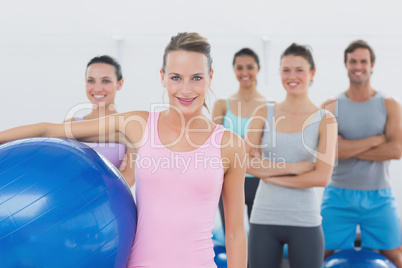 Instructor holding exercise ball with fitness class in backgroun