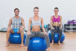 Sporty people sitting on exercise balls at gym