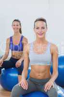 Sporty women sitting on exercise balls in gym