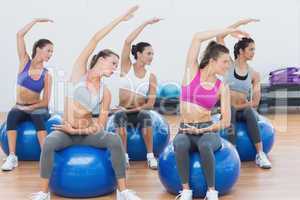 Sporty women stretching out hand on exercise balls at gym