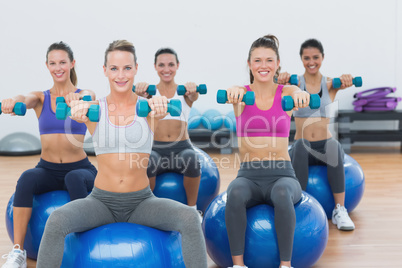 Women exercising with dumbbells on fitness balls Women exercising with dumbbells on fitness balls