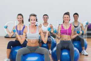 Women exercising with dumbbells on fitness balls