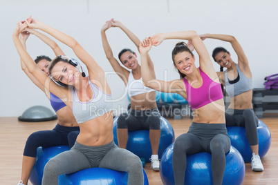 Sporty women stretching up hands on exercise balls at gym