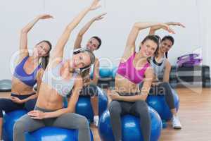 Sporty women stretching hands on exercise balls at gym