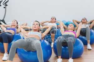 Class doing abdominal crunches on fitness balls
