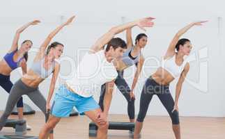 Class doing stretching exercise in fitness studio