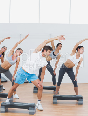 Class doing stretching exercise in fitness studio