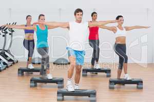 Fitness class performing step aerobics exercise