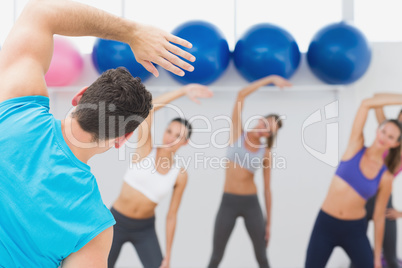 Class doing stretching exercise in fitness studio