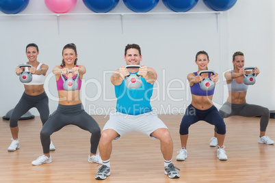 Class and instructor exercising with kettlebells in gym