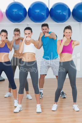 Smiling people doing power fitness exercise at yoga class