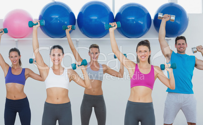 Fitness class exercising with dumbbells in gym