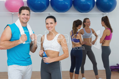 Smiling couple with fitness class in background