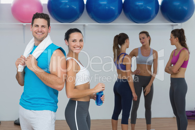 Smiling couple with fitness class in background