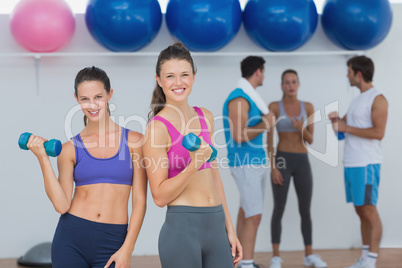 Fit women holding dumbbells with class in background