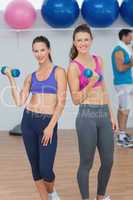 Fit young women holding dumbbells with a man in background