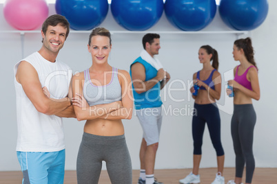 Smiling couple with fitness class in background