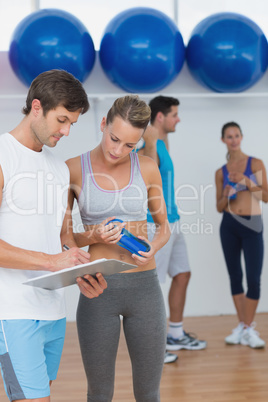 Couple looking at clipboard with fitness class in background