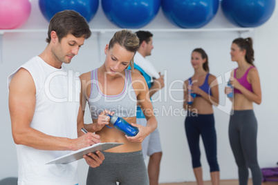 Couple looking at clipboard with fitness class in background