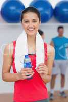 Female holding water bottle with fitness class in background