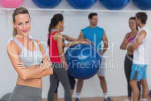 Fit young woman with friends in background at fitness studio