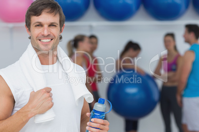Man holding water bottle with friends in background at fitness s