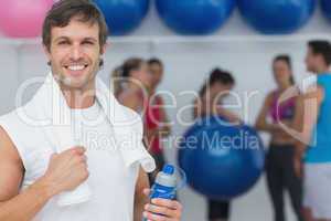 Man holding water bottle with friends in background at fitness s