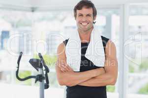 Smiling man standing with arms crossed at spinning class in brig