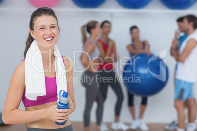 Female holding water bottle with fitness class in background