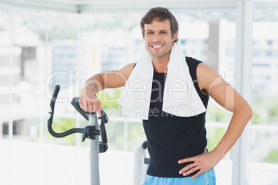 Smiling man standing at spinning class in bright gym