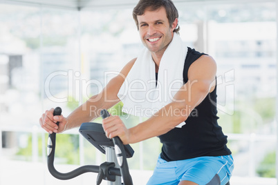 Smiling man working out at spinning class in bright gym