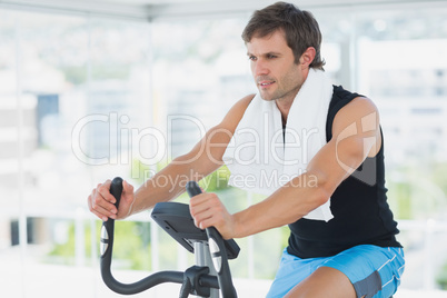 Smiling man working out at spinning class in bright gym