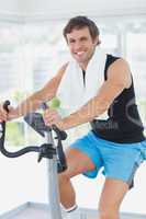 Smiling man working out at spinning class in bright gym