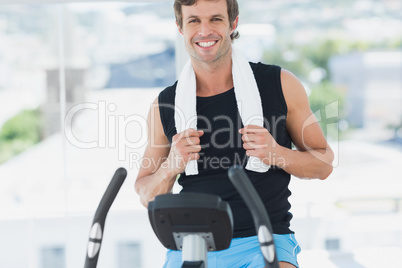 Smiling man working out at spinning class in bright gym