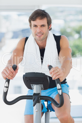 Smiling man working out at spinning class in bright gym