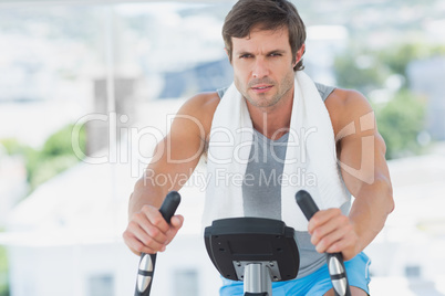 Smiling man working out at spinning class in bright gym