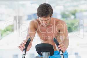 Determined man working out at spinning class in bright gym