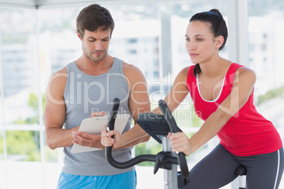 Woman with male instructor working out at spinning class