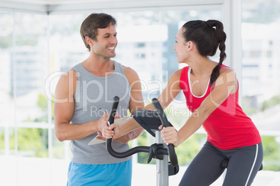 Woman with male instructor working out at spinning class