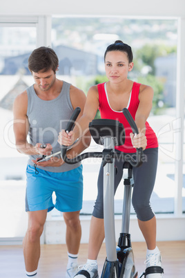 Fit woman with male instructor working out at spinning class