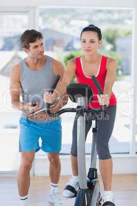 Fit woman with male instructor working out at spinning class