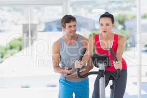 Woman with male instructor working out at spinning class