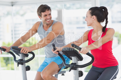 Smiling couple working out at spinning class