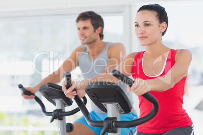 Determined couple working out at spinning class in gym