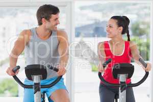 Couple working out at spinning class in bright gym