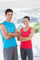 Fit couple with arms crossed in bright exercise room